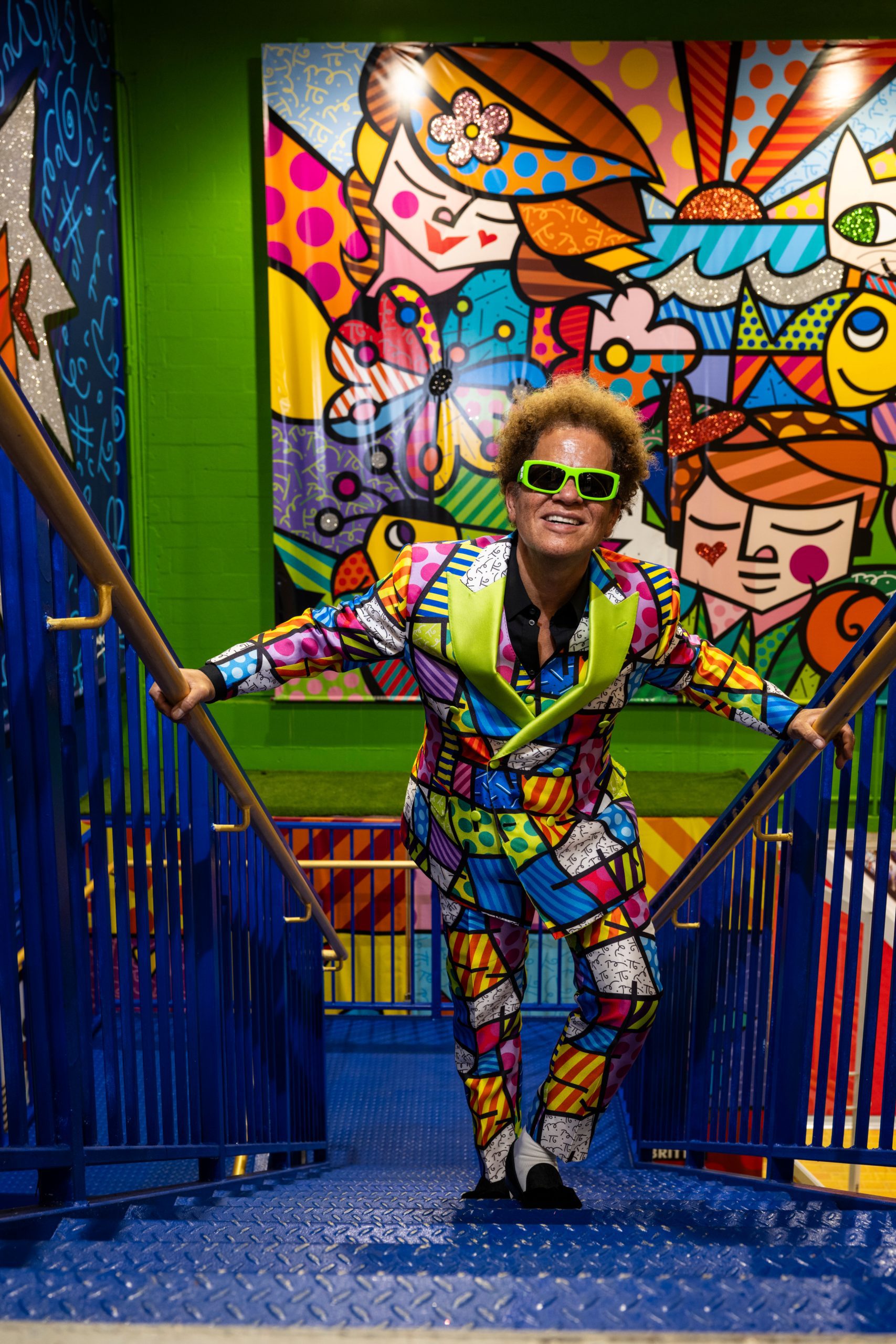 Romero Britto standing on colorful stairs in front of pop art